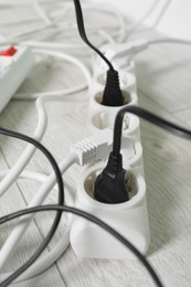 Photo of Power strip with different electrical plugs on white floor, closeup