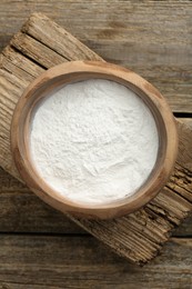 Baking powder in bowl on wooden table, top view