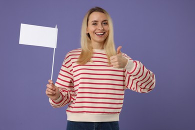 Photo of Happy woman with blank white flag showing thumbs up on violet background. Mockup for design