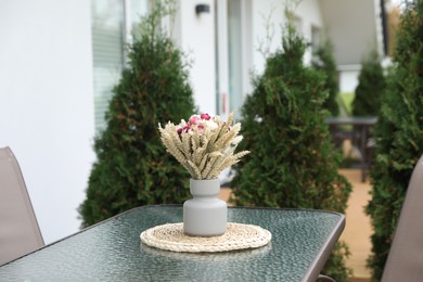 Photo of Beautiful bouquet of dry flowers in vase on glass table outdoors