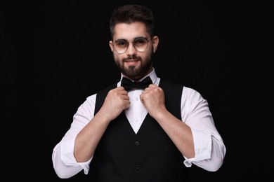 Portrait of smiling man in shirt and bow tie on black background