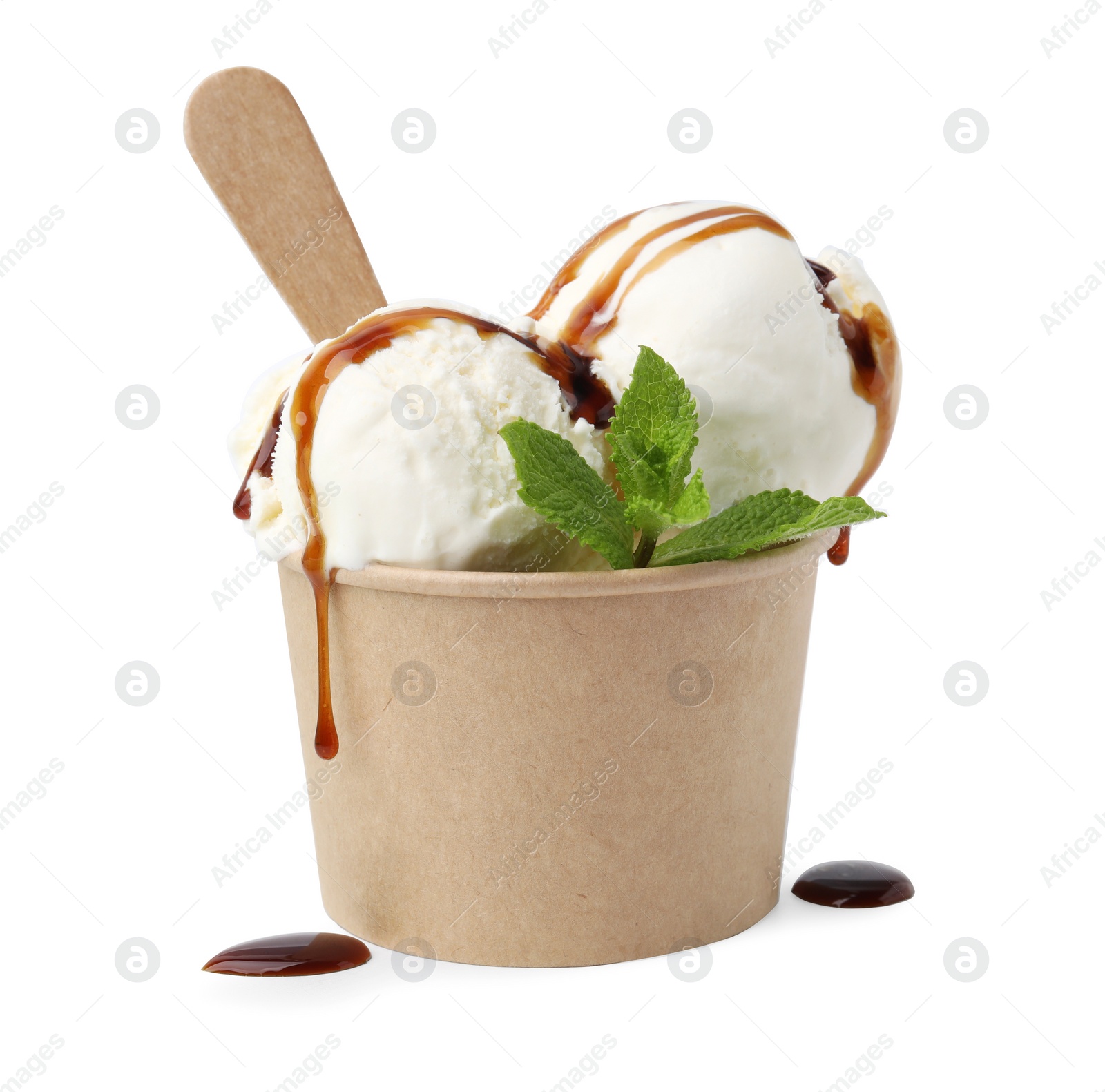 Photo of Scoops of delicious ice cream with caramel sauce and mint in paper cup isolated on white