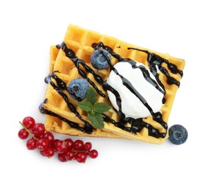 Photo of Tasty Belgian waffles with ice cream, berries and chocolate syrup on white background, top view