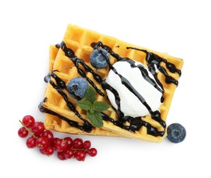 Tasty Belgian waffles with ice cream, berries and chocolate syrup on white background, top view