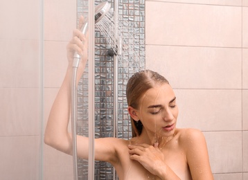 Beautiful young woman taking shower at home