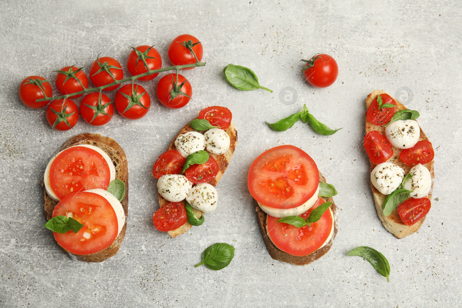 Photo of Delicious sandwiches with mozzarella, fresh tomatoes and basil on light grey table, flat lay