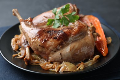 Tasty cooked rabbit meat with vegetables and parsley on table, closeup