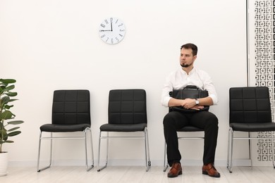 Photo of Man sitting on chair and waiting for job interview indoors