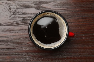 Cup of aromatic coffee on wooden table, top view