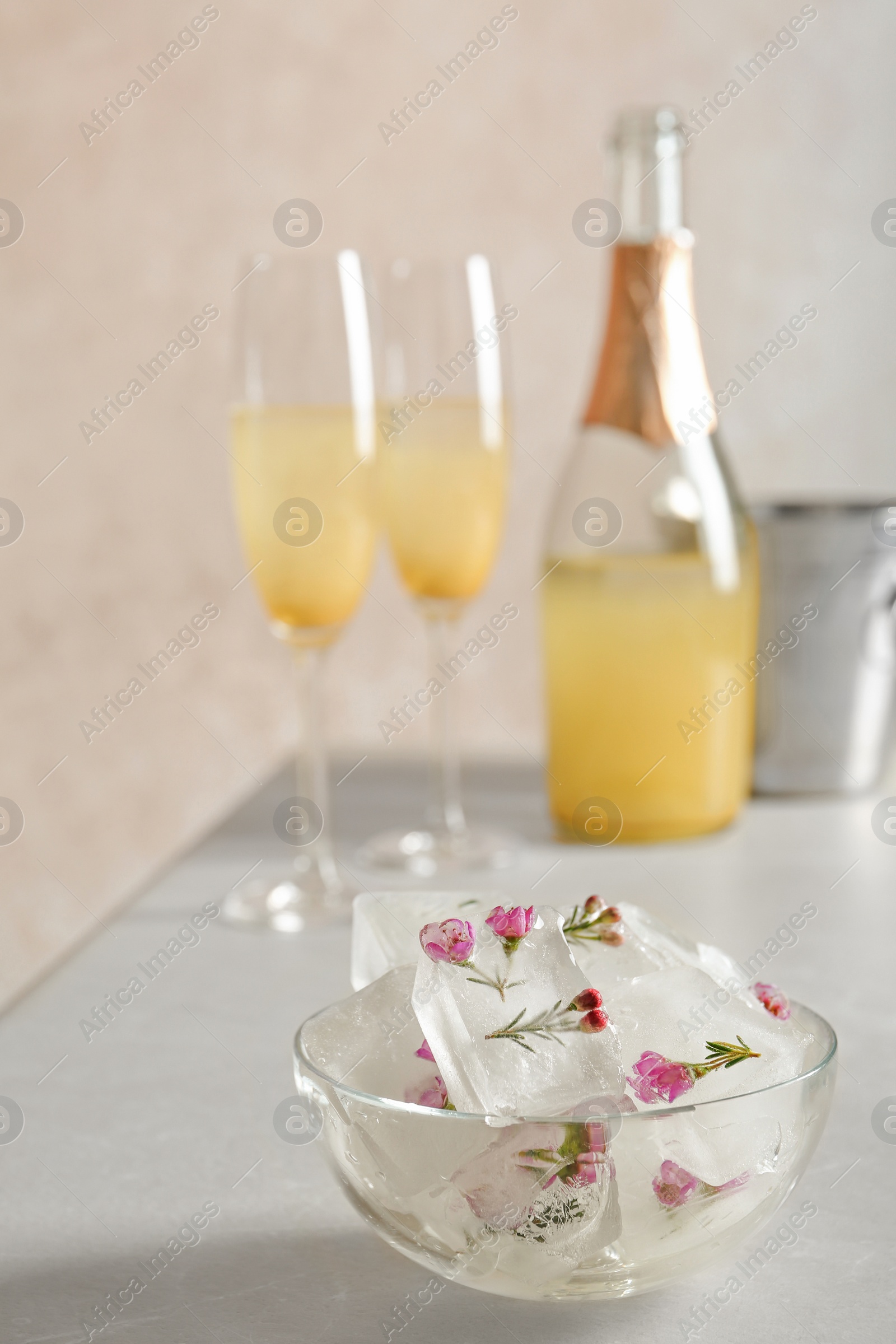 Photo of Bowl with floral ice cubes on table. Space for text