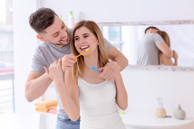 Photo of Young couple brushing teeth together in bathroom