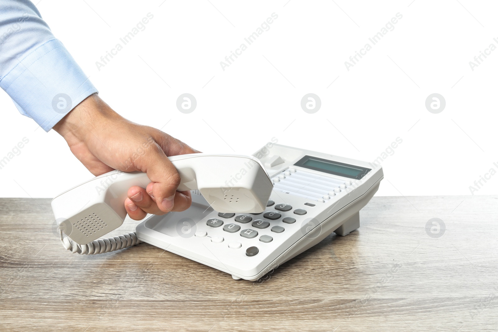 Photo of Man dialing number on telephone at table against white background, closeup