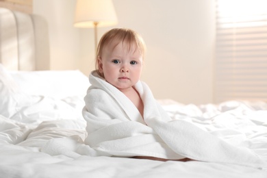 Photo of Cute little baby with soft towel on bed after bath