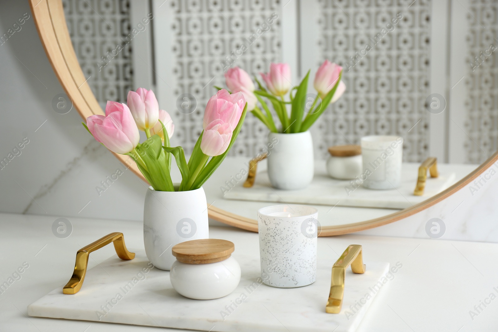 Photo of Beautiful flowers and candle on countertop in bathroom. Interior decor