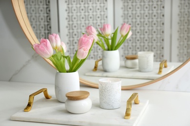 Photo of Beautiful flowers and candle on countertop in bathroom. Interior decor
