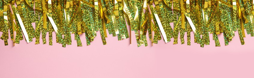 Image of Golden tinsel on pink background, top view. Banner design