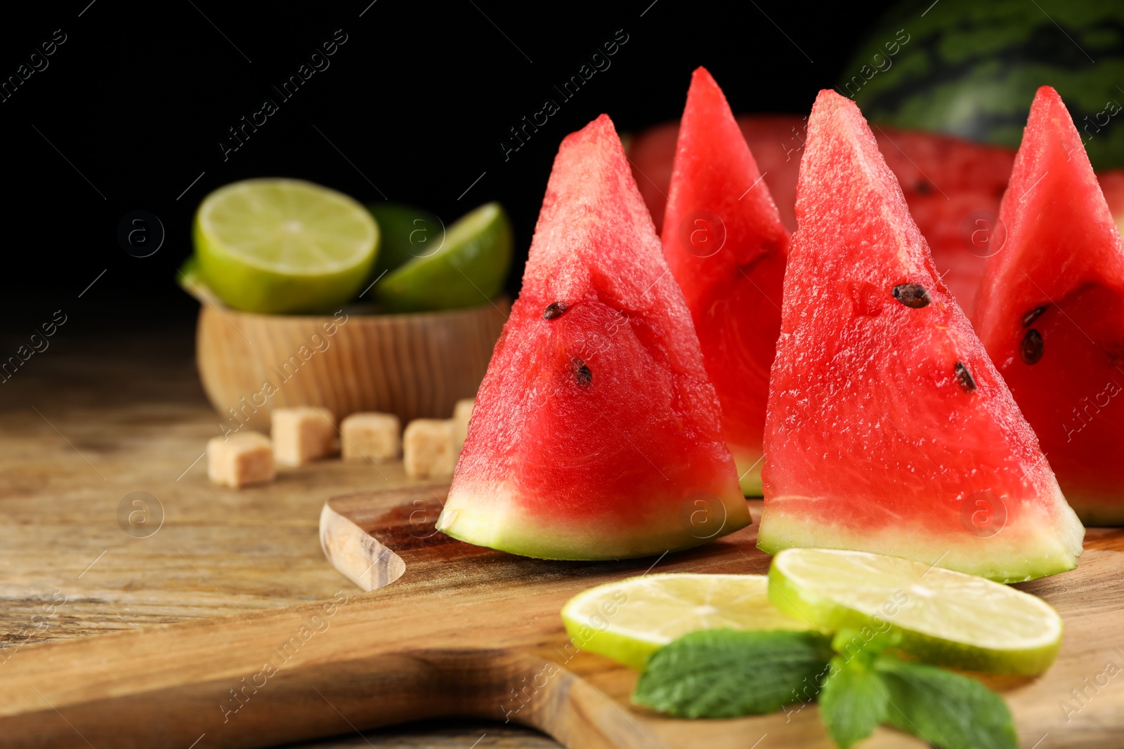 Photo of Board with juicy watermelon and lime slices on wooden table, closeup. Space for text