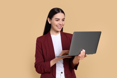 Photo of Happy woman using laptop on beige background