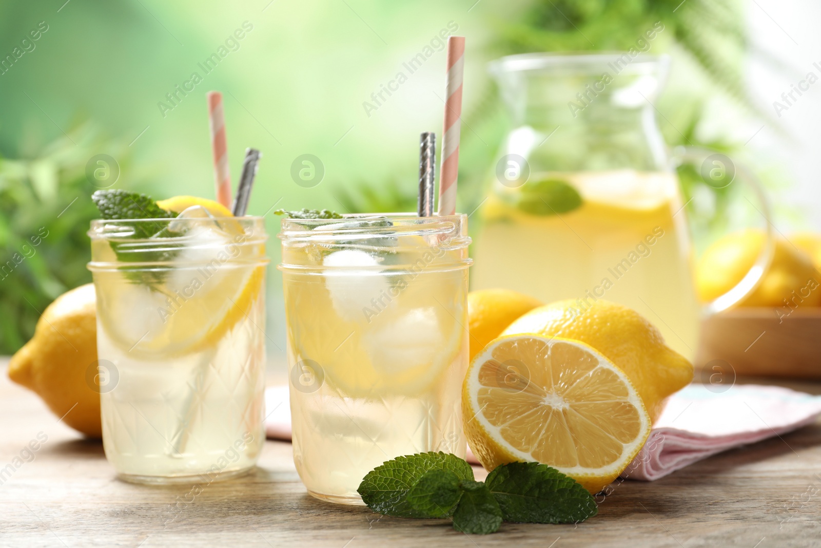 Photo of Natural lemonade with mint and fresh fruits on wooden table. Summer refreshing drink