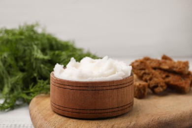 Photo of Delicious pork lard in bowl on wooden board, closeup