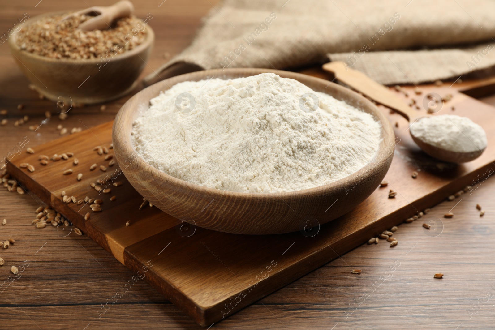 Photo of Plate with wheat flour on wooden table