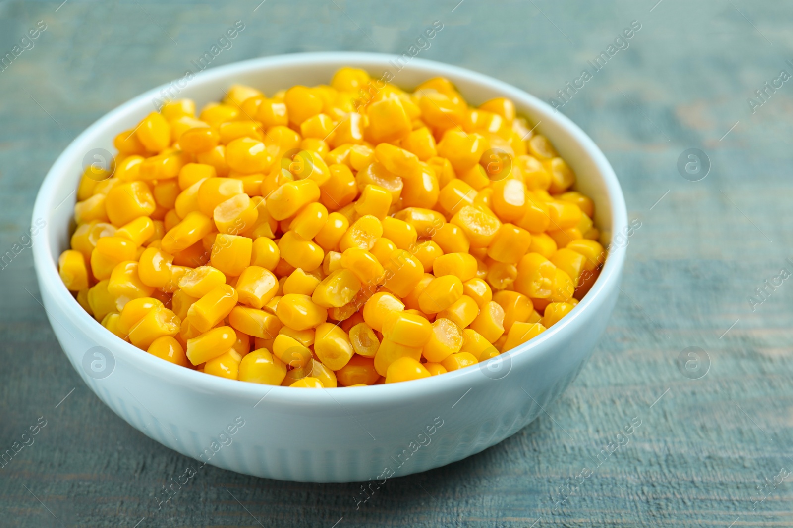 Photo of Tasty canned sweet corn on blue wooden table, closeup