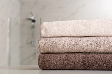 Photo of Stack of clean towels on table in bathroom, closeup. Space for text