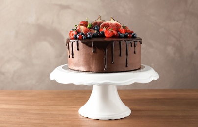 Photo of Fresh delicious homemade chocolate cake with berries on table against color background