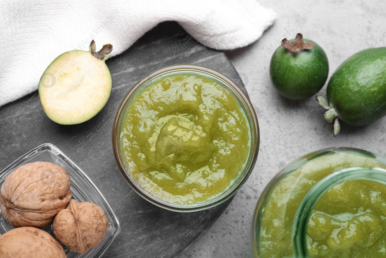 Photo of Feijoa jam and fresh fruits on grey table, flat lay