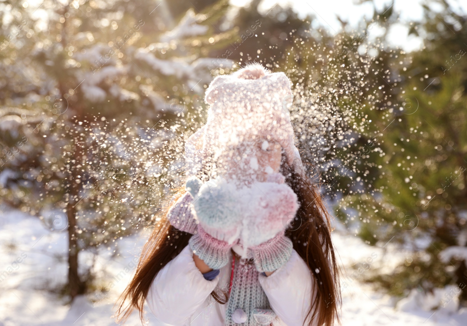 Photo of Cute little girl playing with snow in winter forest