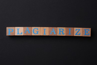 Wooden cubes with word Plagiarize on black background, flat lay