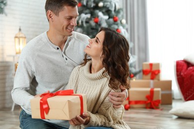 Image of Happy couple with Christmas gift at home