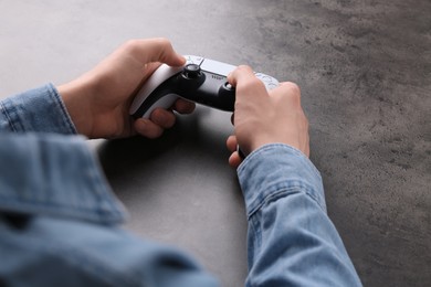 Photo of Man using wireless game controller at grey table, closeup