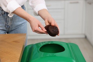Photo of Garbage sorting. Woman throwing muffin liner into trash bin indoors, closeup