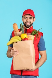 Photo of Man holding paper bag with fresh products on color background. Food delivery service