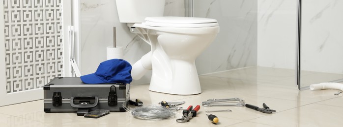 Plumber's tools near toilet bowl in bathroom. Banner design