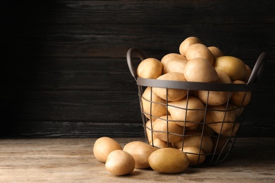 Photo of Raw fresh organic potatoes on wooden table against dark background. Space for text