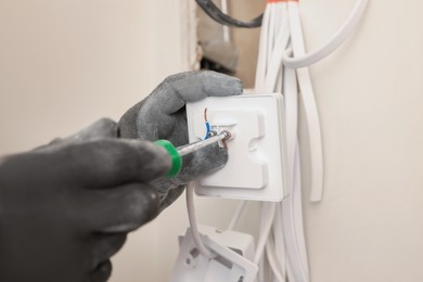 Photo of Electrician installing remote meter with screwdriver indoors, closeup
