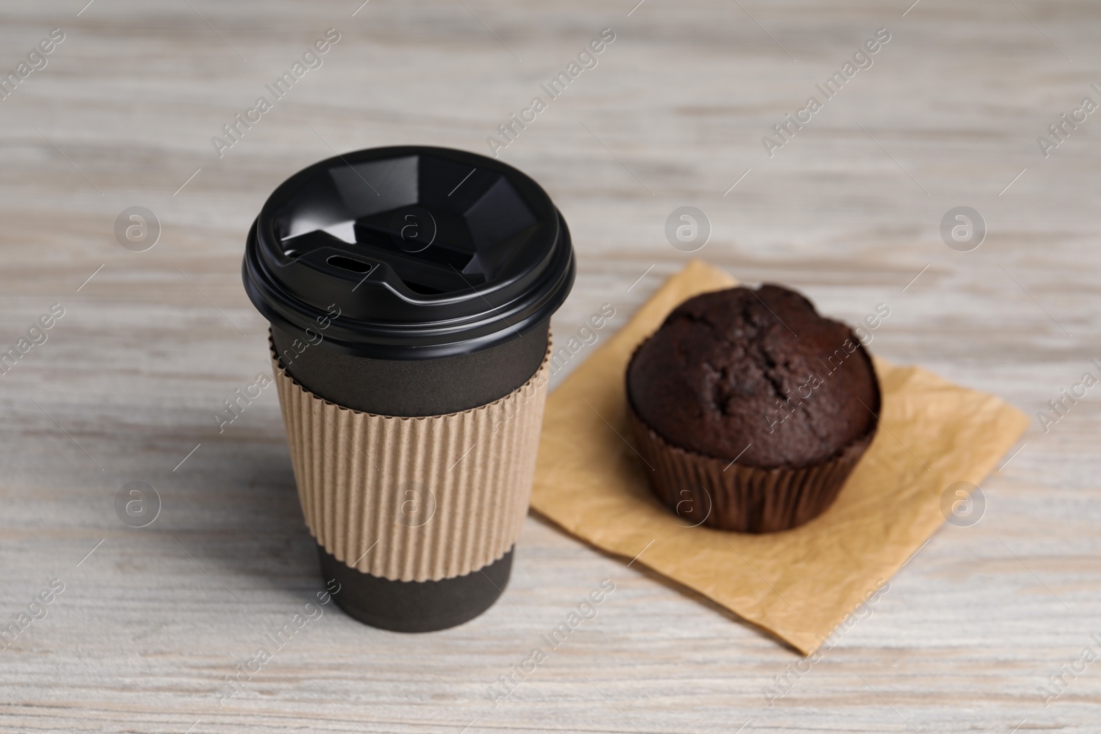 Photo of Paper cup with black lid and muffin on wooden table. Coffee to go