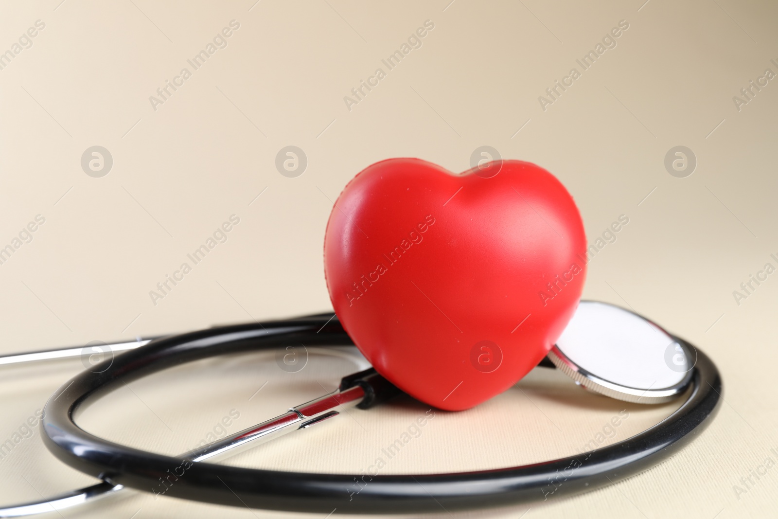 Photo of Stethoscope and red heart on beige background