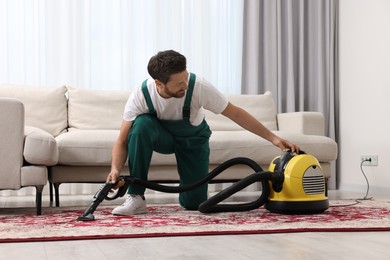 Photo of Dry cleaner's employee hoovering carpet with vacuum cleaner in room