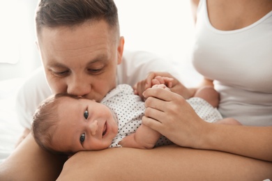 Photo of Happy couple with their newborn baby on light background