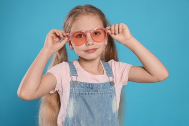 Girl in pink sunglasses on light blue background