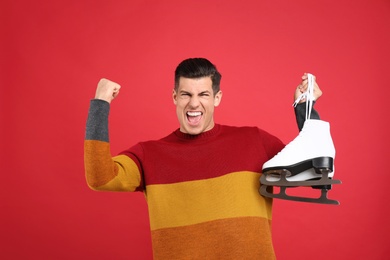 Emotional man with ice skates on red background