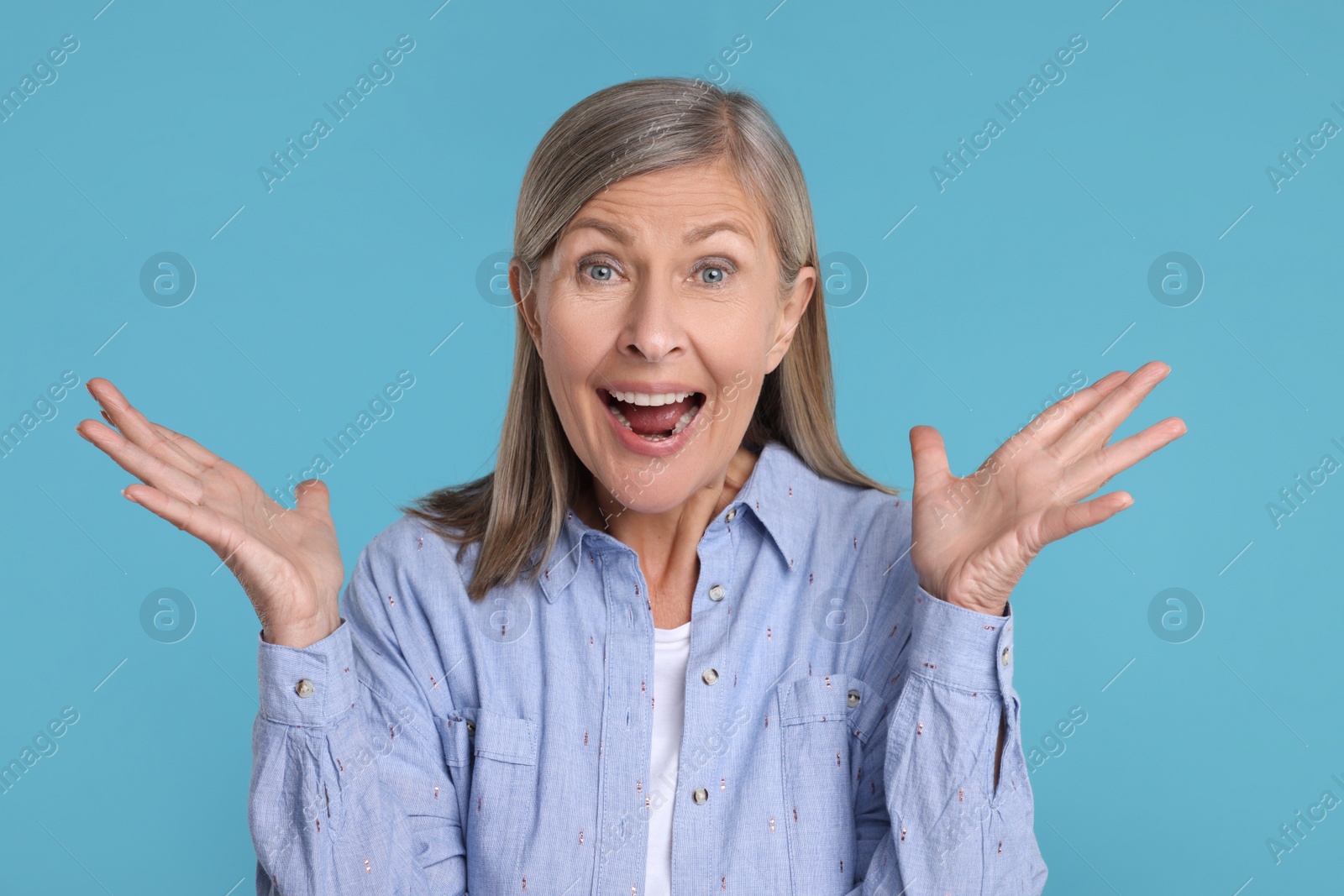 Photo of Portrait of happy surprised senior woman on light blue background