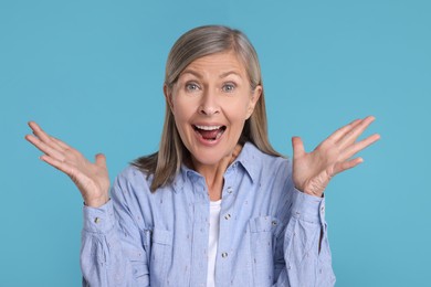 Portrait of happy surprised senior woman on light blue background