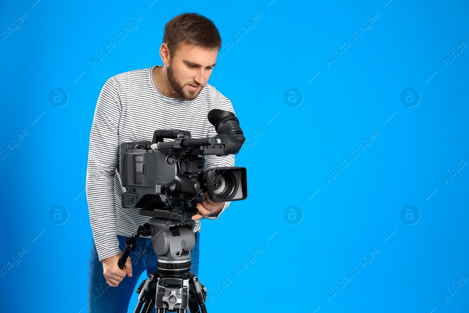 Photo of Operator with professional video camera on blue background, space for text