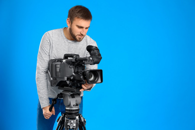 Operator with professional video camera on blue background, space for text