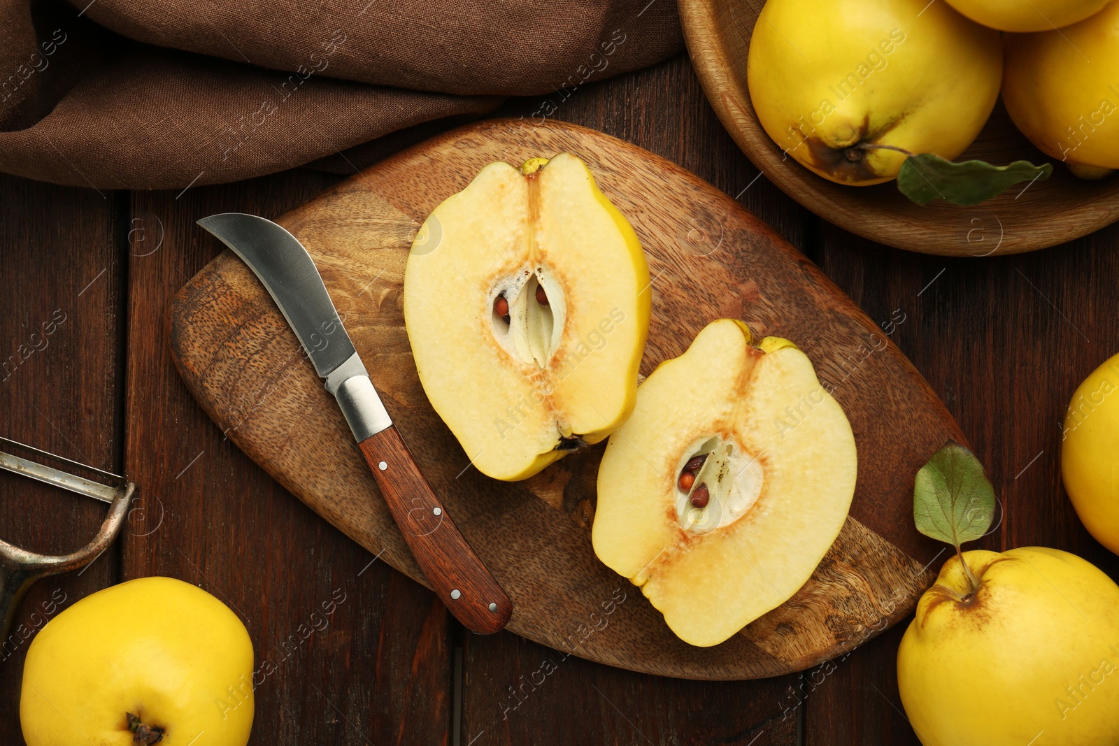 Photo of Tasty ripe quince fruits, peeler and knife on wooden table, flat lay