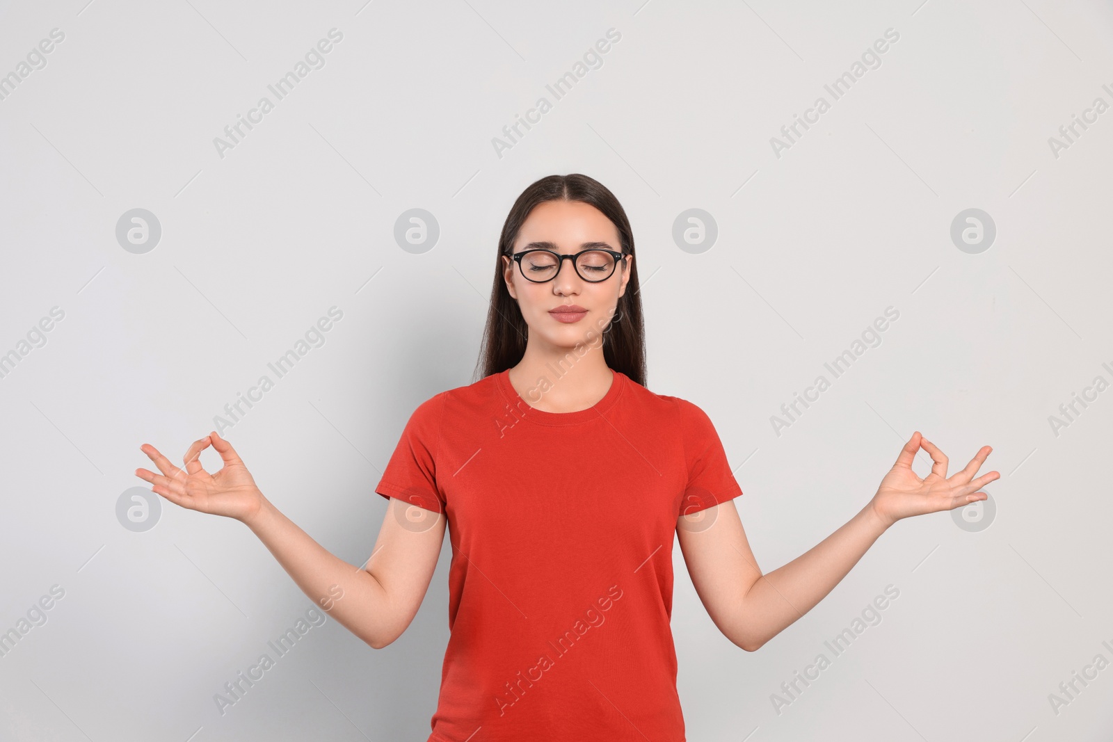 Photo of Find zen. Beautiful young woman meditating on white background